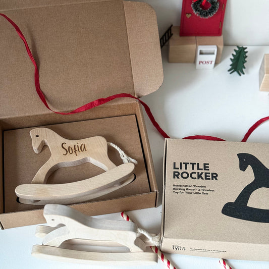 Wooden toy rocker with 'Sofia' engraving in a brown box, surrounded by festive decor.