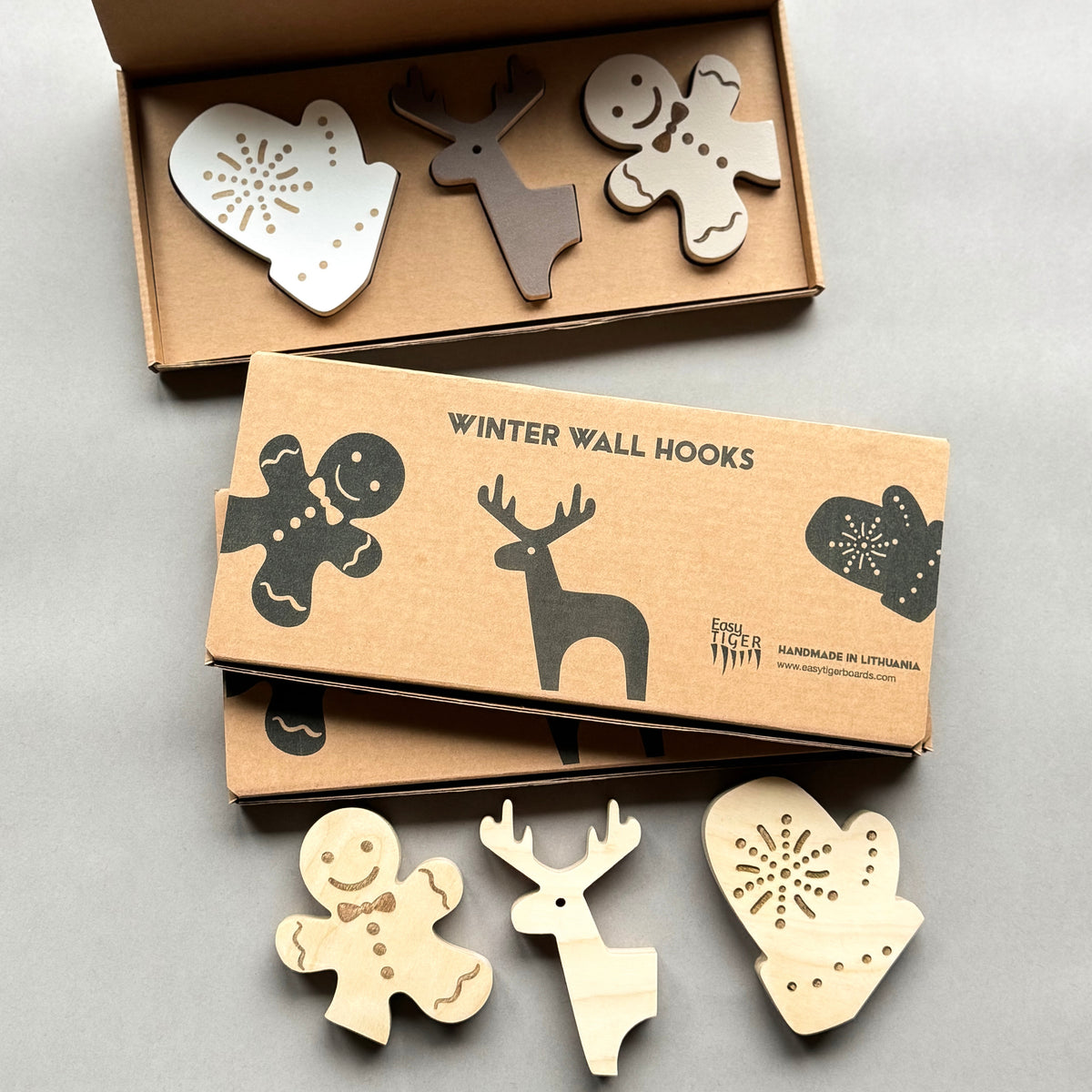 Set of wooden winter-themed wall hooks in a cardboard box on a light gray background
