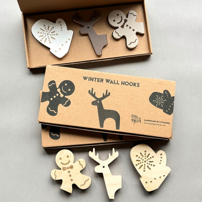Set of wooden winter-themed wall hooks in a cardboard box on a light gray background