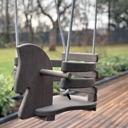 Wooden swing on a wooden deck with blurred trees in the background