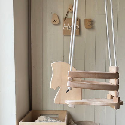 Wooden baby swing, storage box, and toys in a child's room with wooden wall decor.