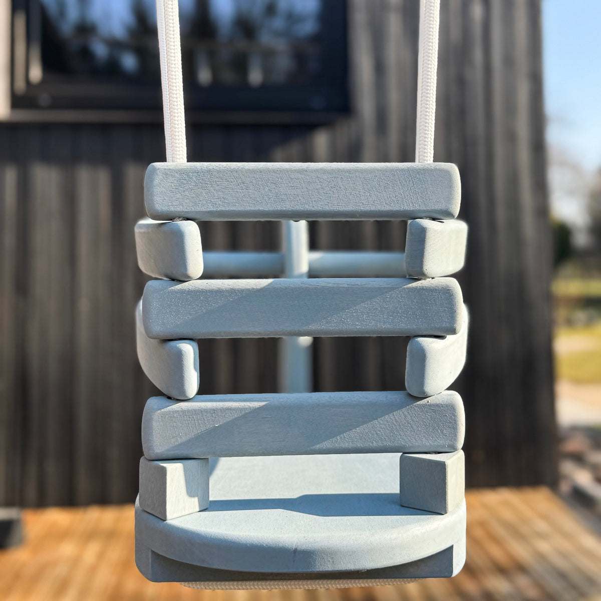 Children's swing set in front of a wooden building