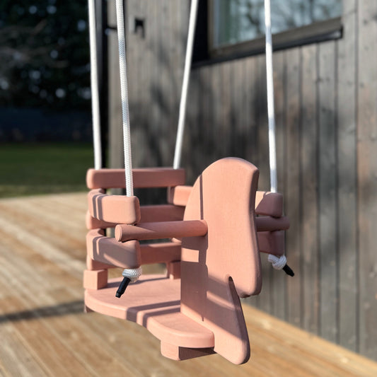 Wooden swing set on a wooden deck with a blurred background