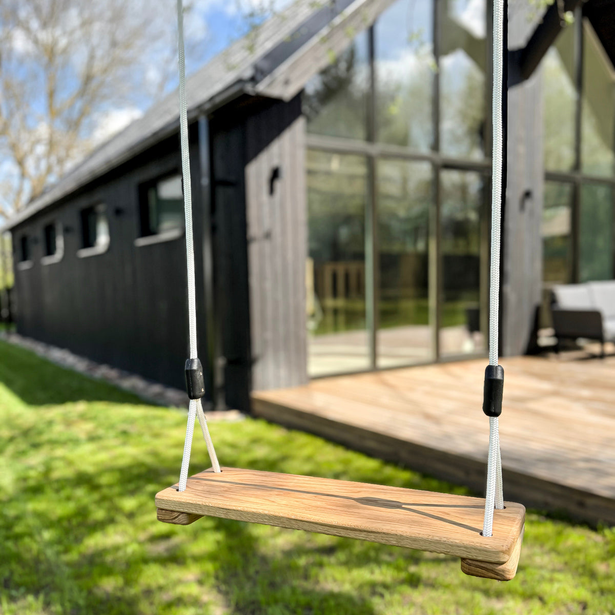 Wooden swing in front of a modern house with large glass windows