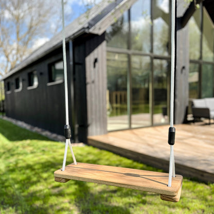 Wooden swing in front of a modern house with large glass windows