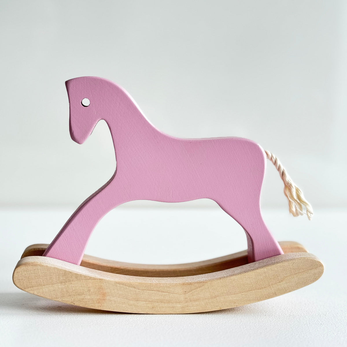 Pink wooden rocking horse on a light gray background
