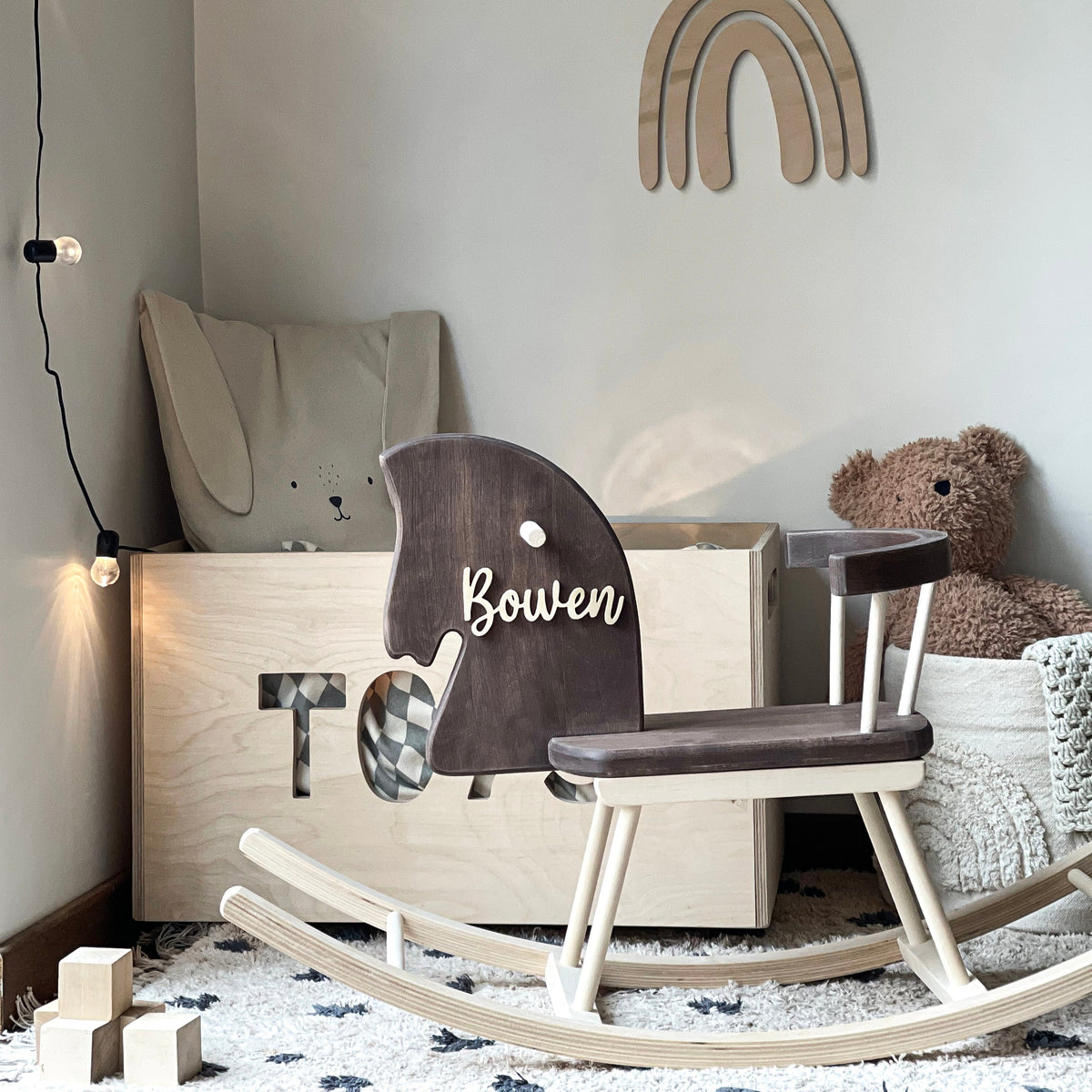Children's playroom with a rocking horse, toy box, and decorative elements on a light gray wall.