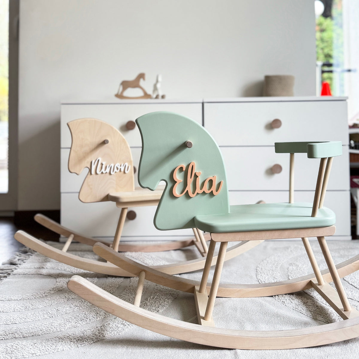 Wooden rocking chair with personalized name on a light-colored floor.