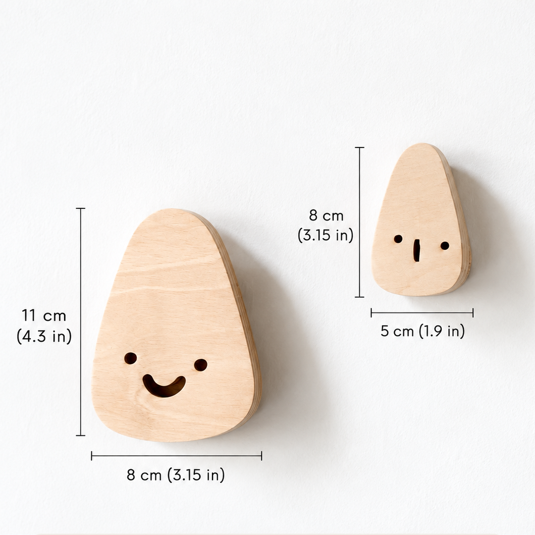 Two small wooden teardrop-shaped wall hooks with simple engraved facial features, shown on a white background with dimension callouts indicating sizes.